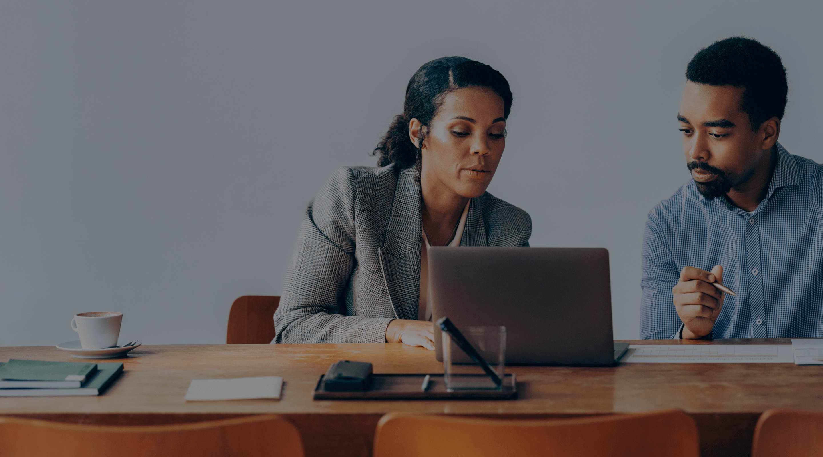 Image of two people looking at a laptop at a table.