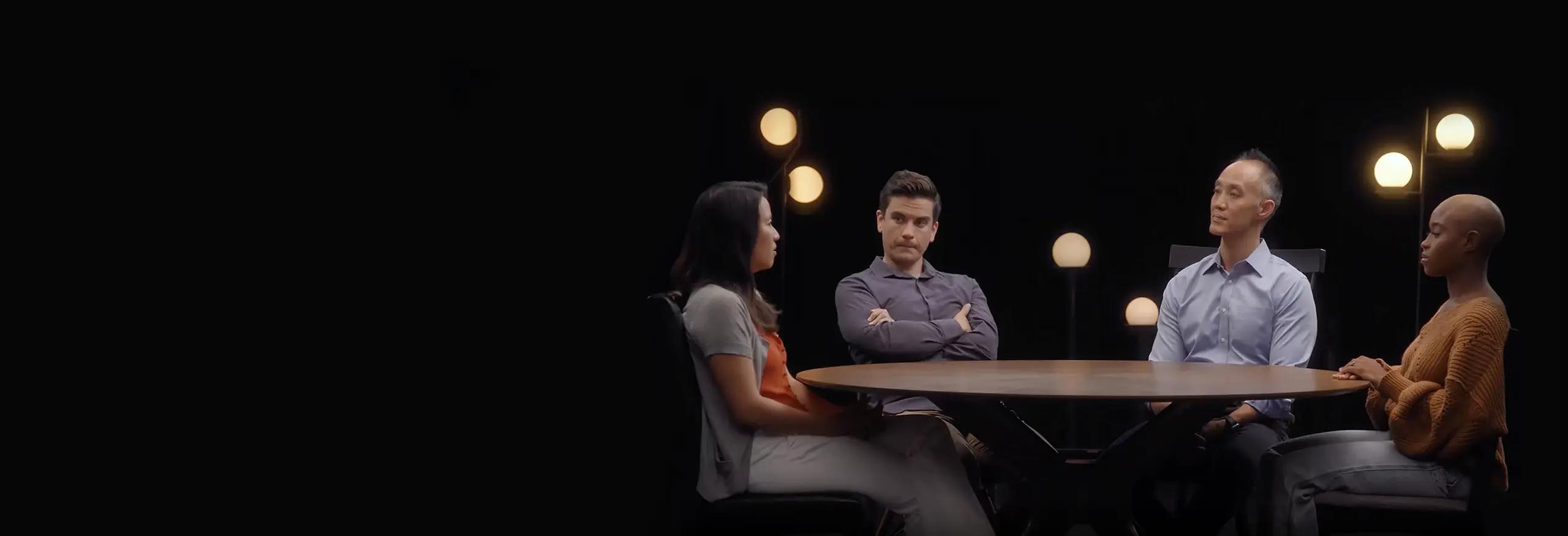 Imagen de cuatro personas sentadas en una mesa discutiendo.